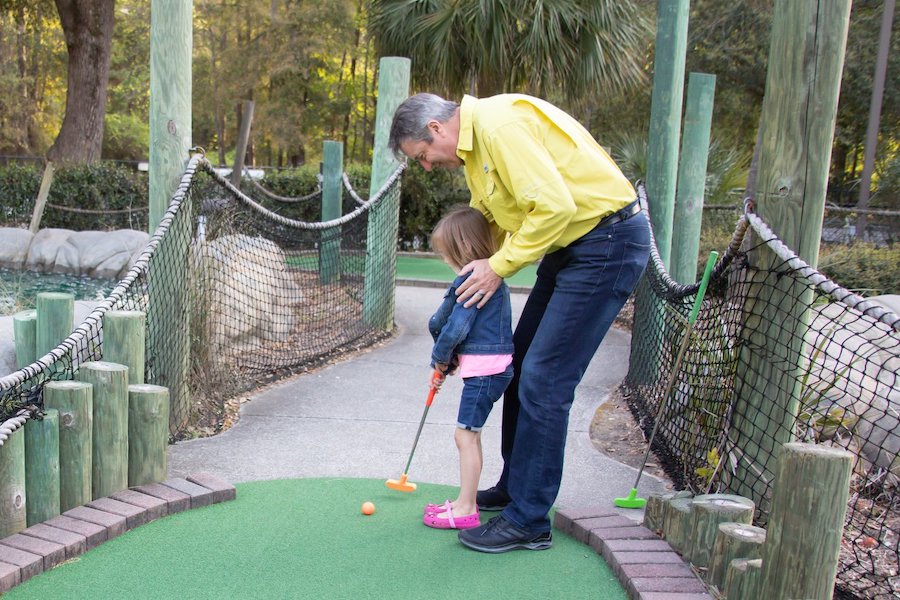 Father and daughter play mini golf at Charleston Fun Park.